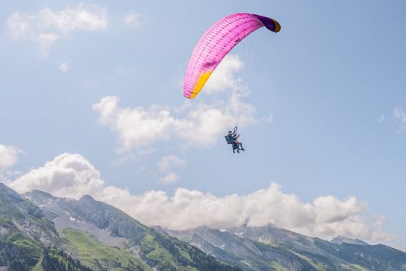 Experience the thrill of paragliding over the stunning Alps on a bright day.